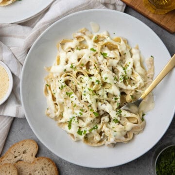 A bowl of pasta noodles tossed with cottage cheese alfredo sauce, black pepper and parsley.