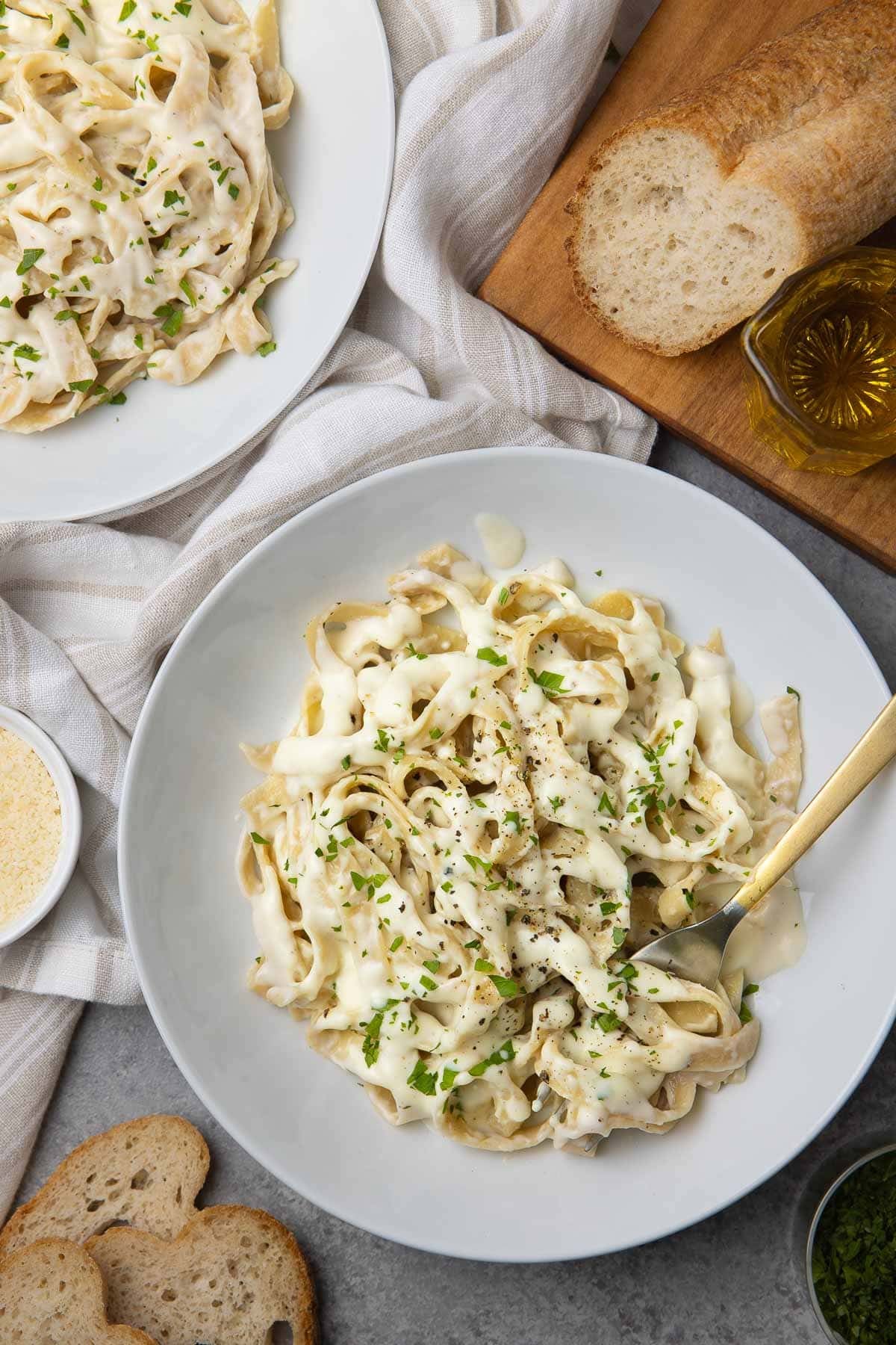 Bowls of fettuccine tossed with creamy cottage cheese alfredo sauce sprinkled with pepper and parsley. 