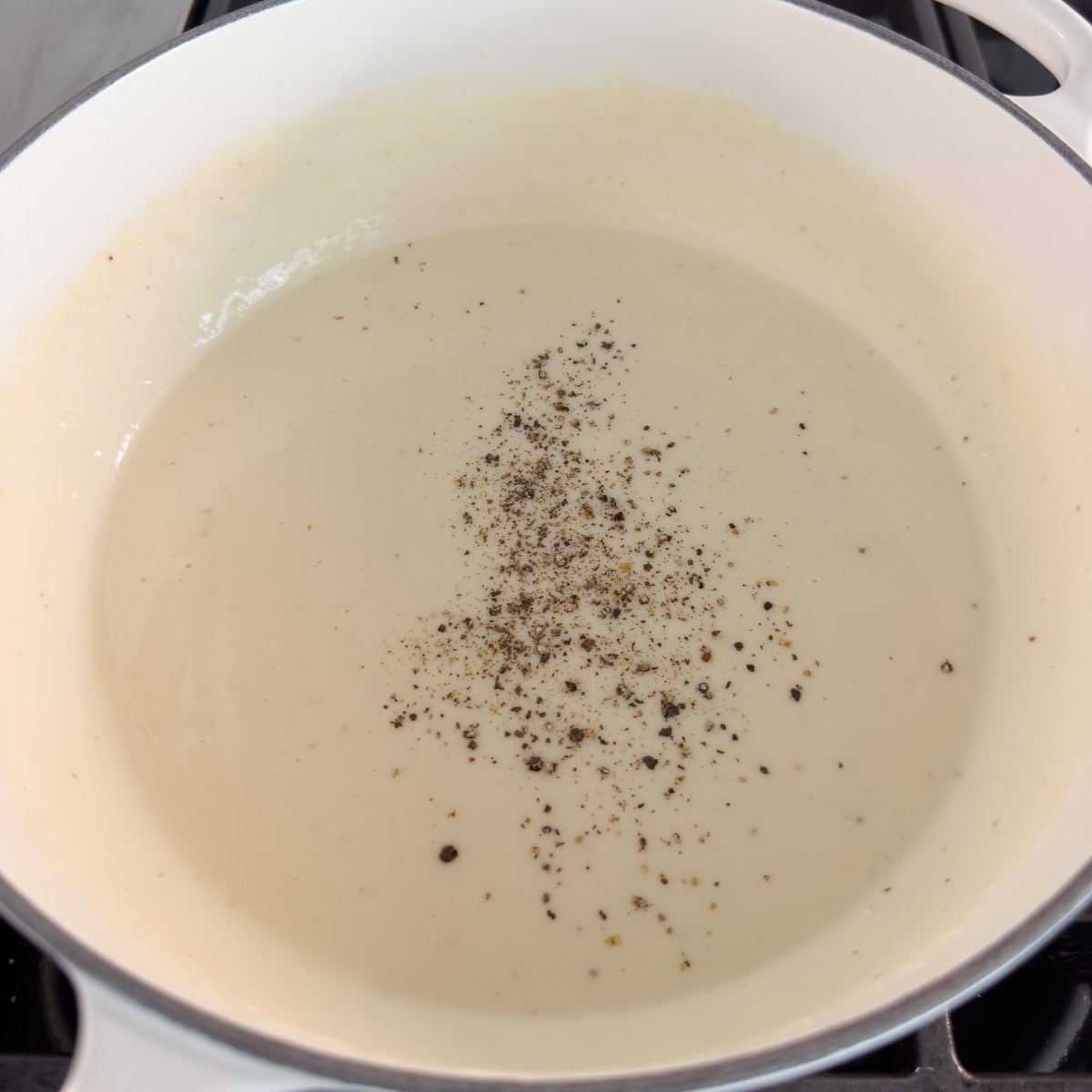 Black pepper on top of a cheese sauce to season.