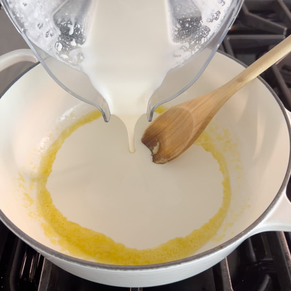 Pouring pureed cottage cheese and milk into a pan to make an alfredo sauce.