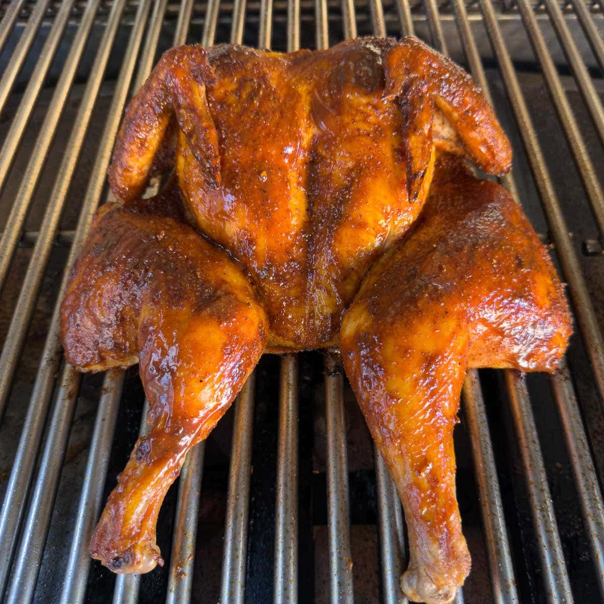 A smoked spatchcock chicken glazed with BBQ sauce, beautifully bronzed and finished.