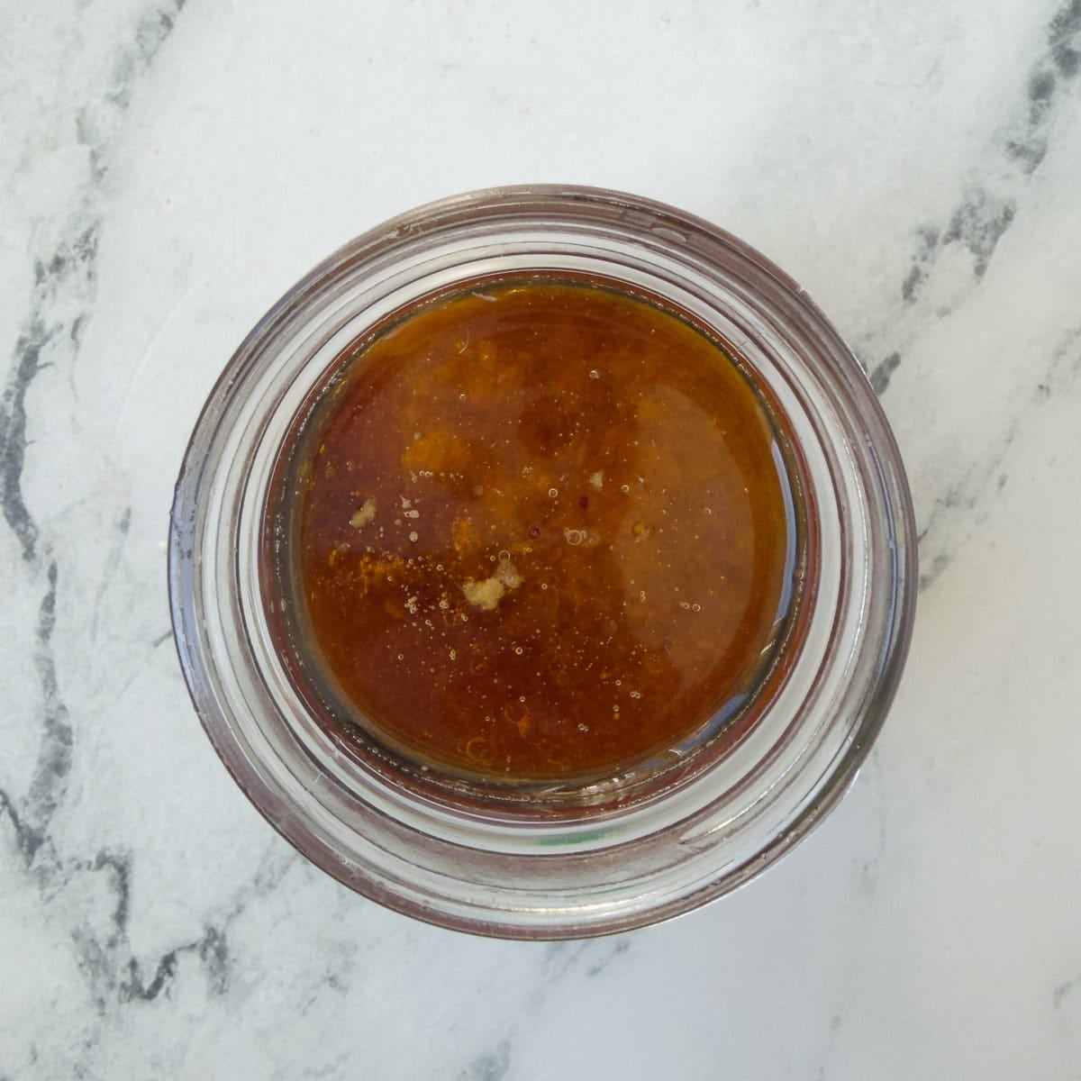 Sesame oil, ginger, garlic, and ingredients to make a dressing, in a glass jar.