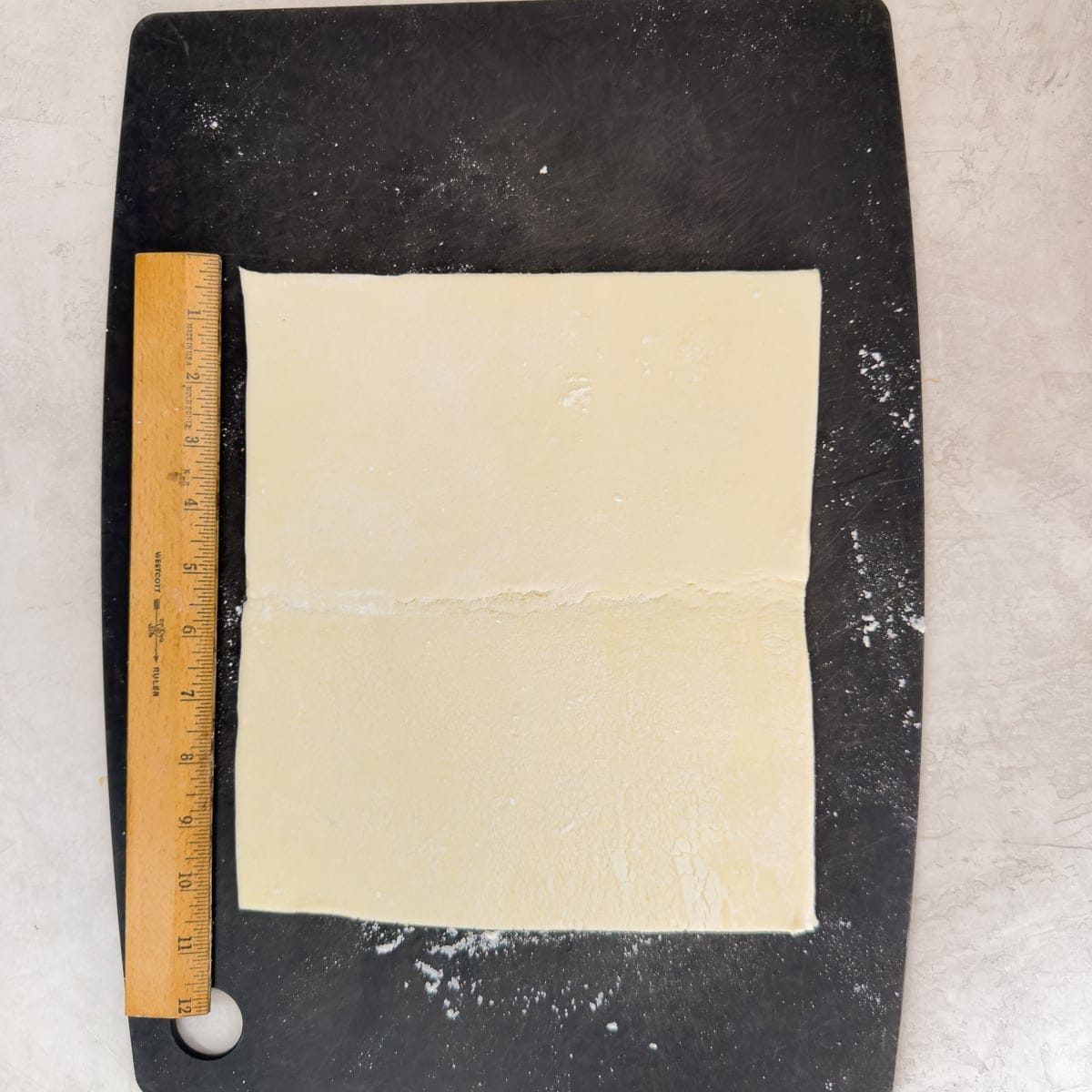 Rolling puff pastry to a square with a ruler for the correct size.