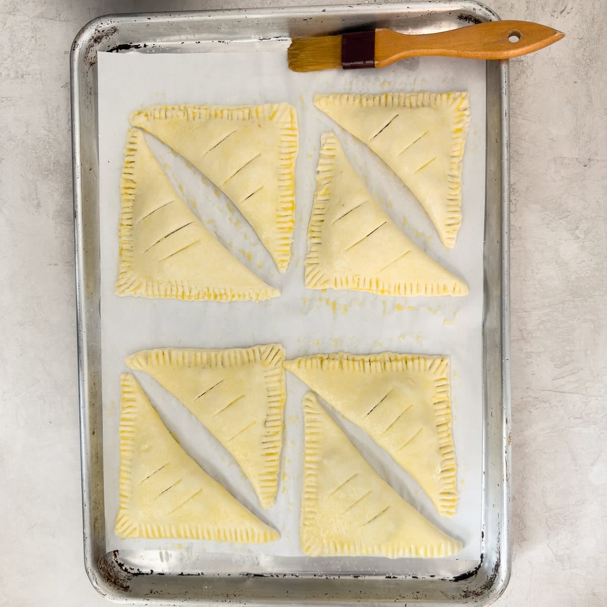 Apple turnovers brushed with egg wash ready for baking.