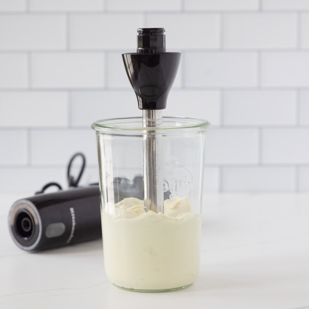 A jar of creamy, ivory, avocado oil mayonnaise with a stick blender in the top.