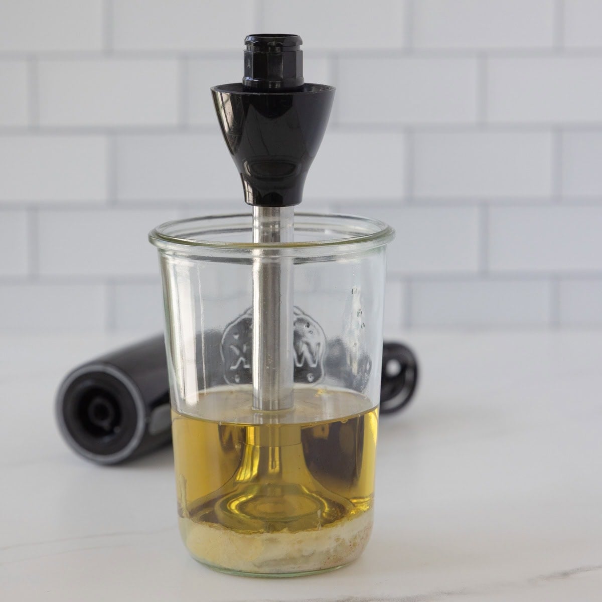 Ingredients for homemade mayonnaise in a jar with an immersion blender in it.
