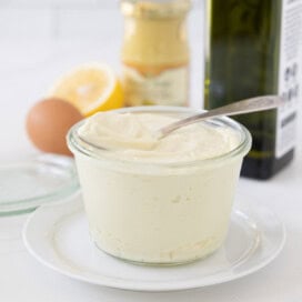A jar of creamy avocado oil mayonnaise with a spoon on top and swirl of mayo.
