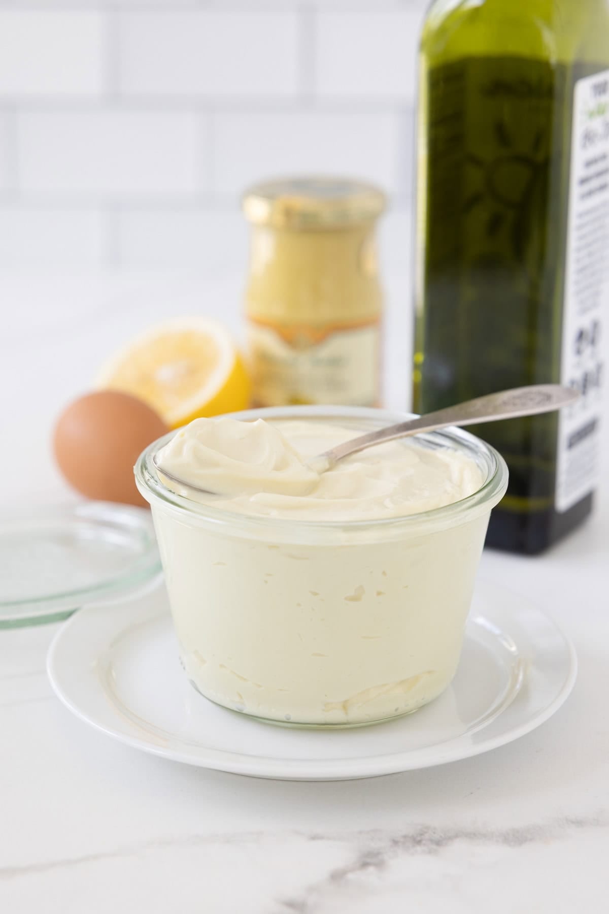 A jar of freshly made creamy avocado oil mayonnaise with a spoon in the top.