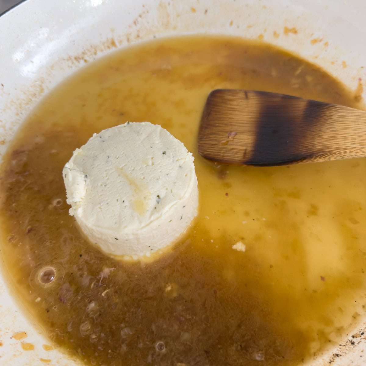 Broth and boursin cheese round starting to cook into a sauce. 