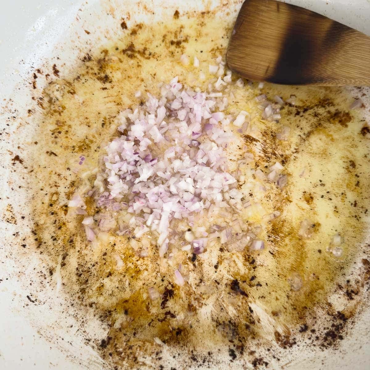 Saut&eacute;ing shallots in olive oil in a braising pan. 