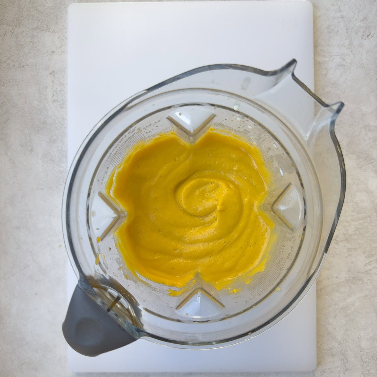 Bright orange pureed butternut pasta sauce in a blender container.