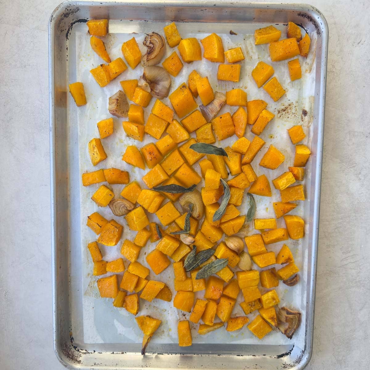 Butternut squash and vegetables on a baking tray after roasting.