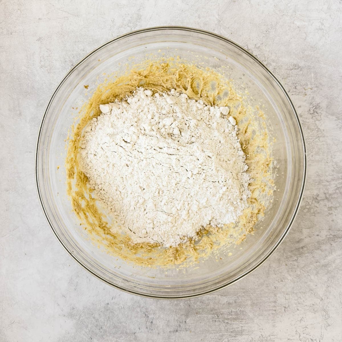 Flour blend added to a bowl with creamed butter, eggs, and sugar.