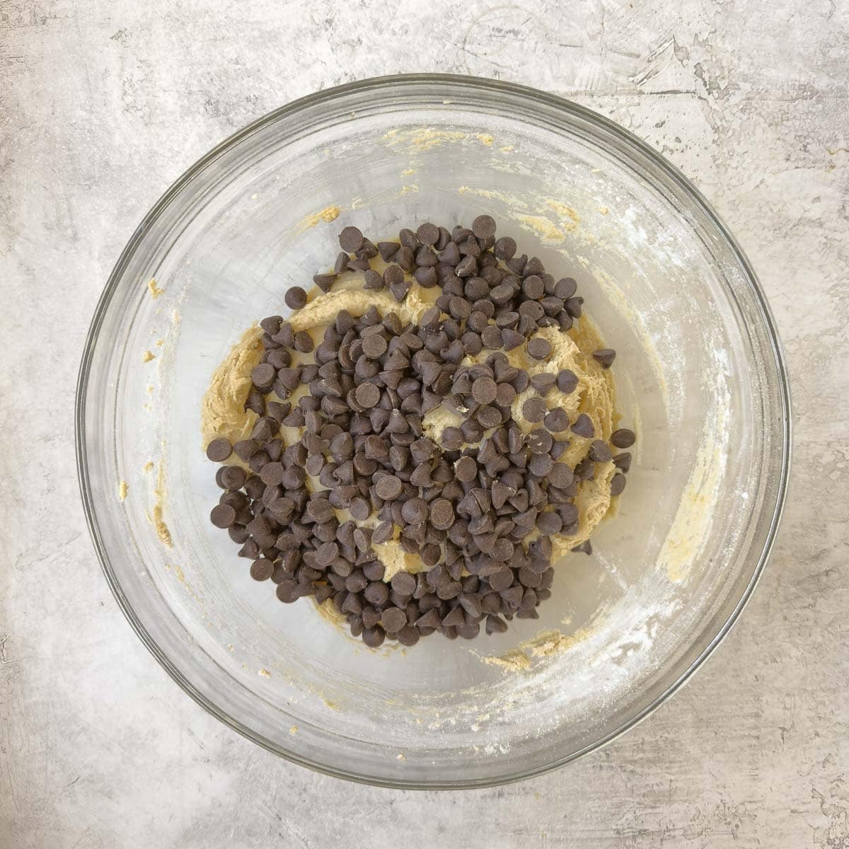 Chocolate chips added to a bowl of creamed cookie dough.