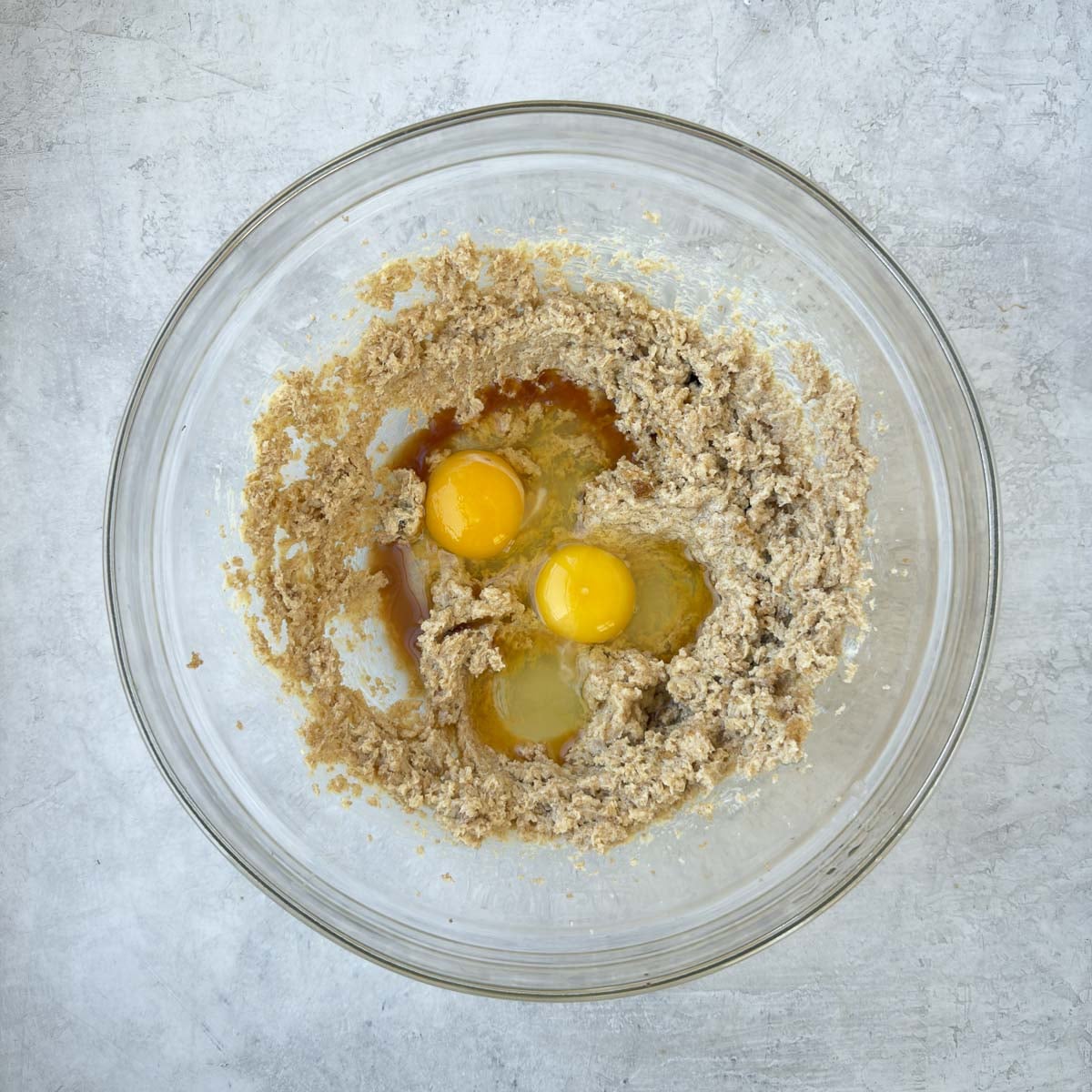 Adding eggs and vanilla to the wet ingredients for chocolate chip cookie dough.
