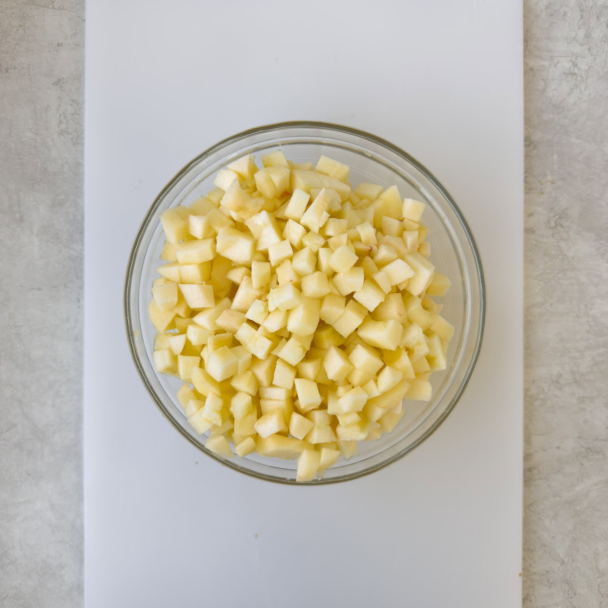Peeled and chopped apples in a glass bowl.