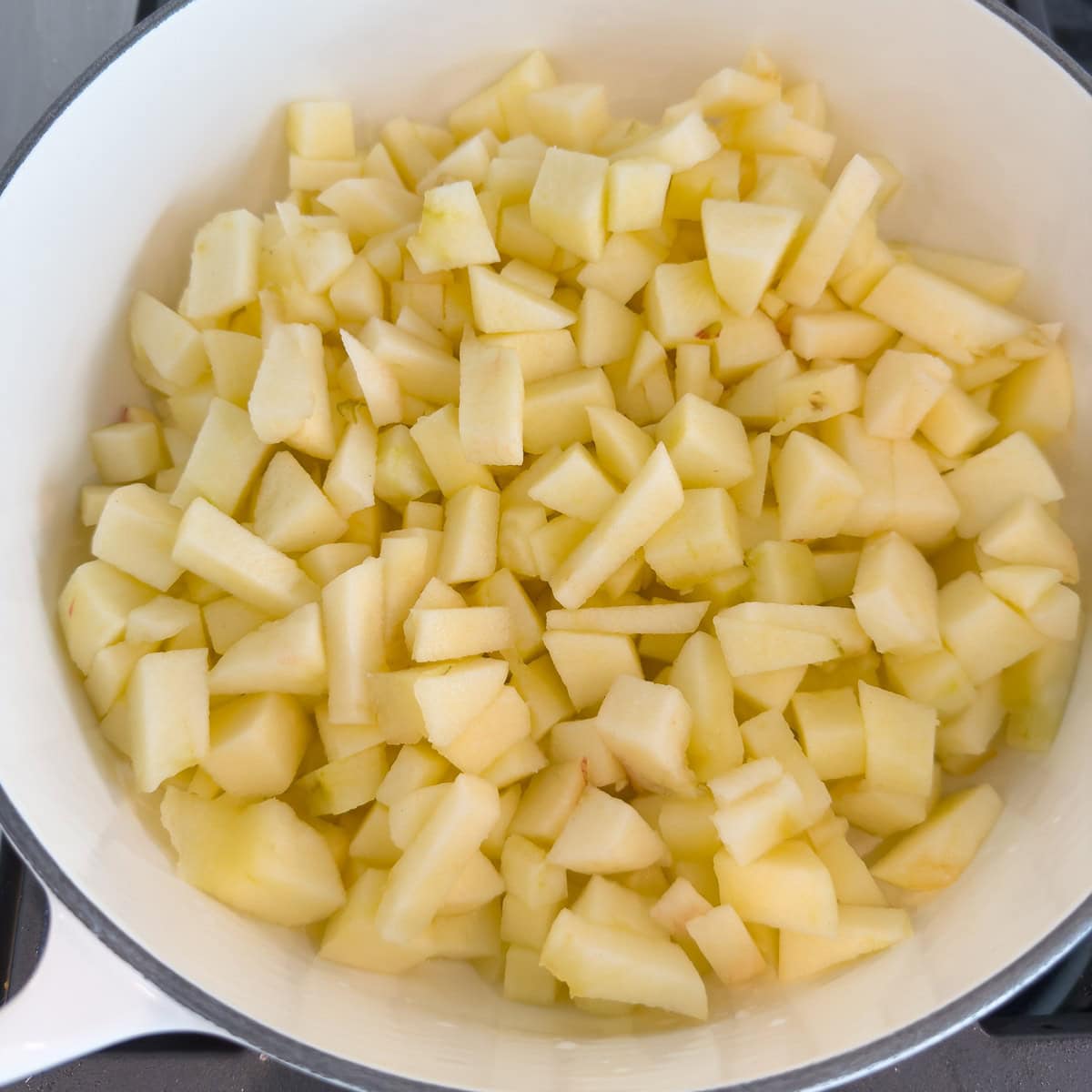 Peeld and chopped apples tp make applesauce in a pan for cooking.