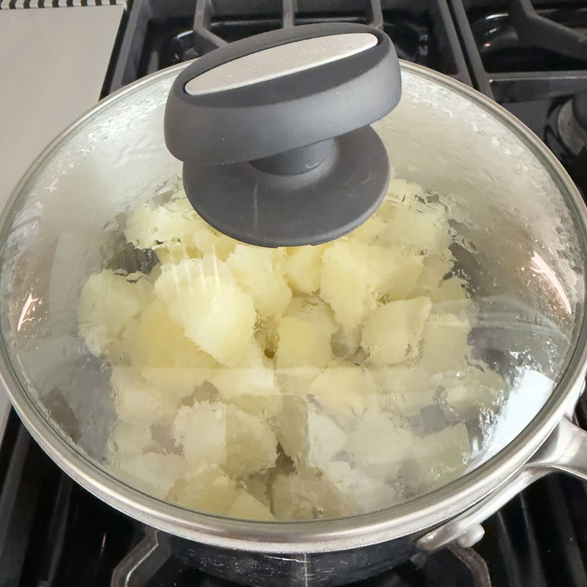 Hot cooked russets drying in a warm pan with a glass lid.