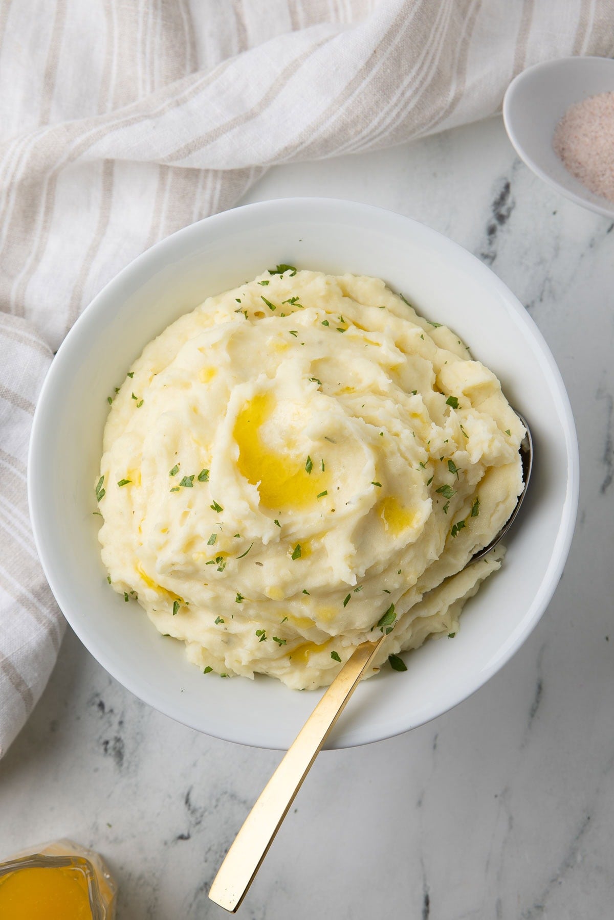A bowl of creamy Boursin whipped potatoes sprinkled with parsley and melted butter.