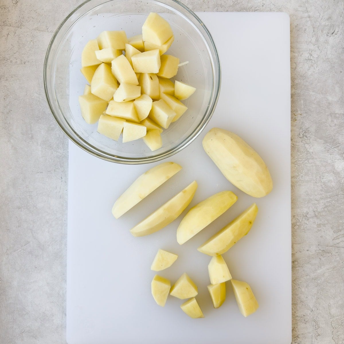 Peeled russet potatoes being chopped for mashed potatoes.