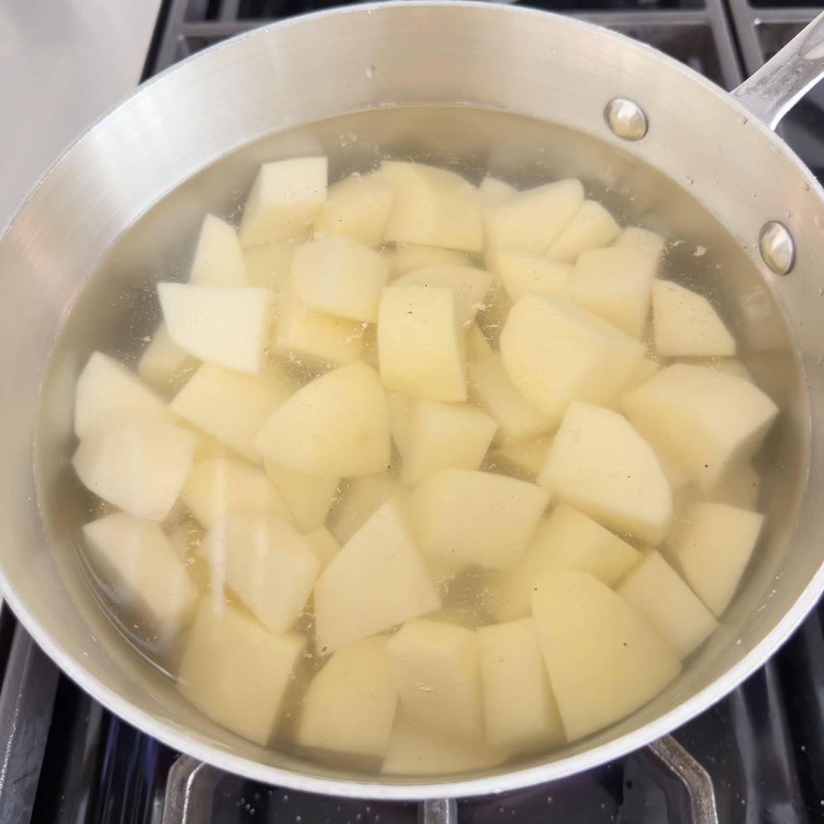 Chopped potatoes in a pan covered with water to cook.