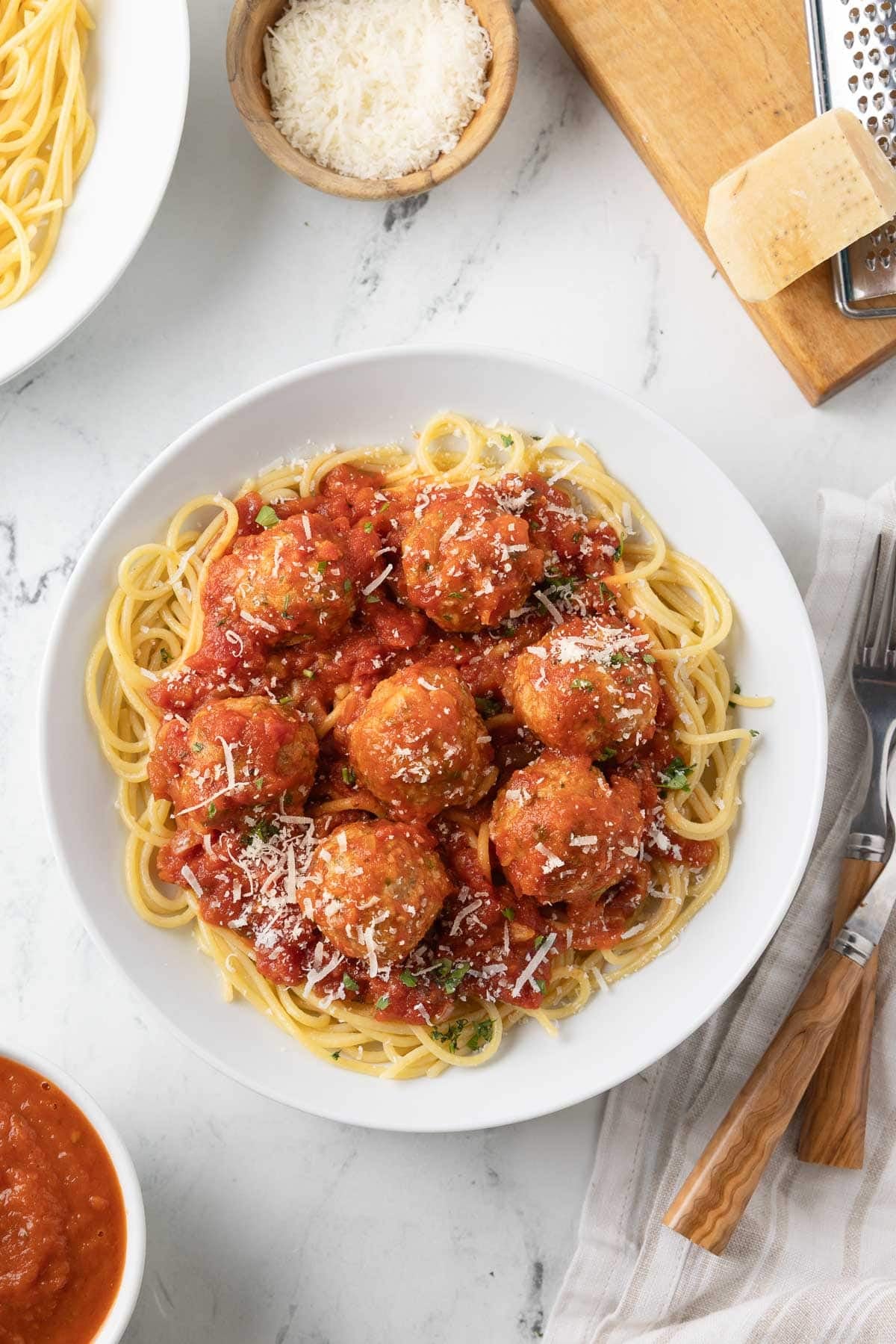 A bowl of spaghetti topped with ricotta meatballs and red pasta sauce with a sprinkle of parmesan.