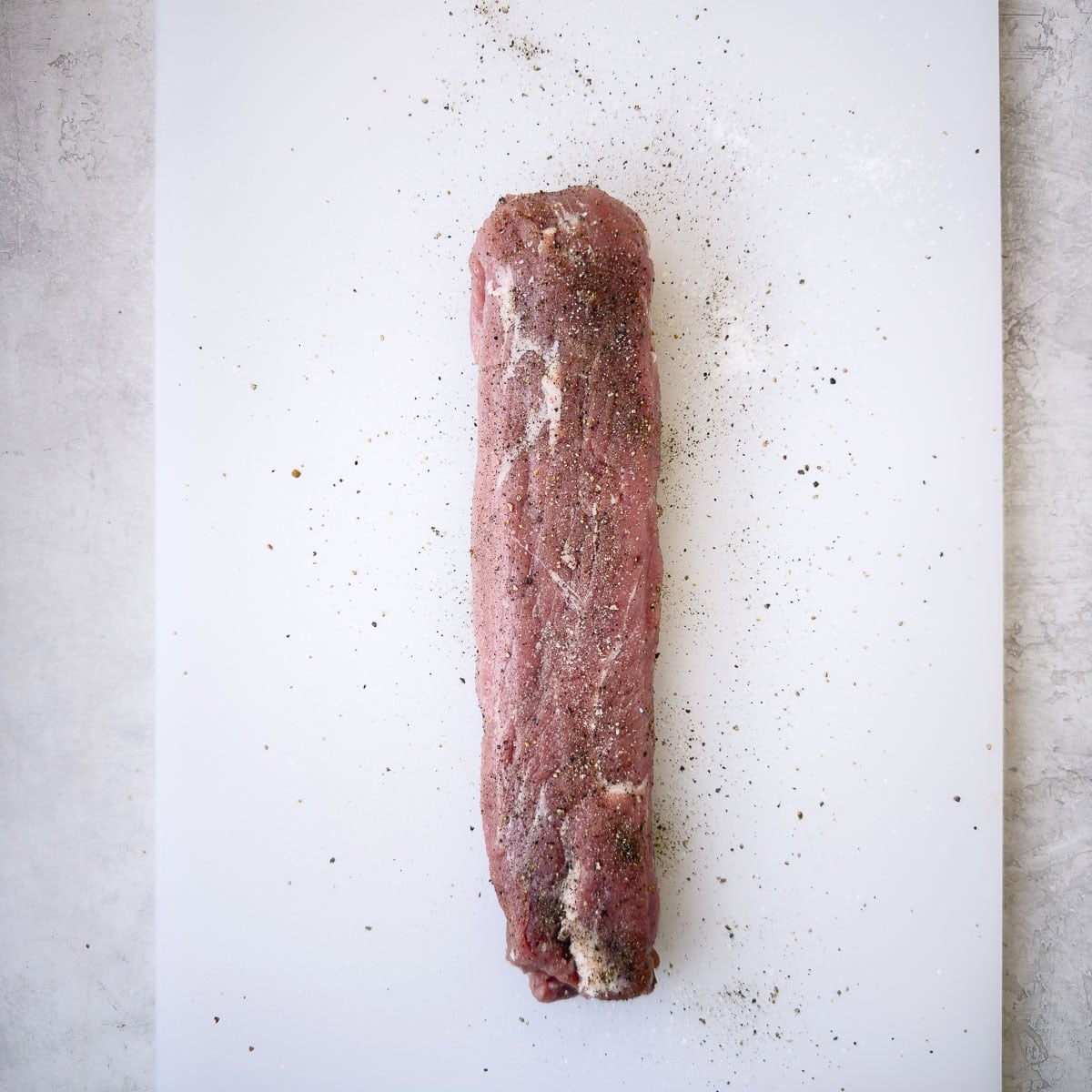 Seasoning pork tenderloin with salt and pepper.