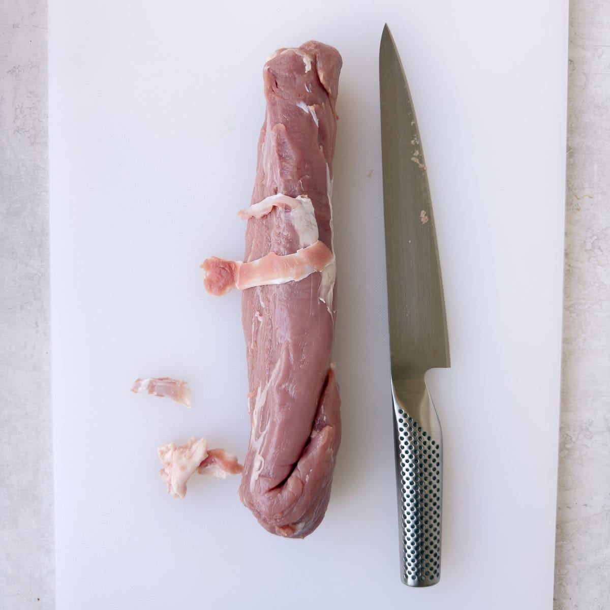 Trimming the silverskin from a pork tenderloin with a knife.